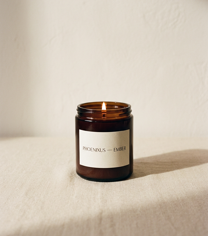 The Ember Candle, lit, on a linen cloth