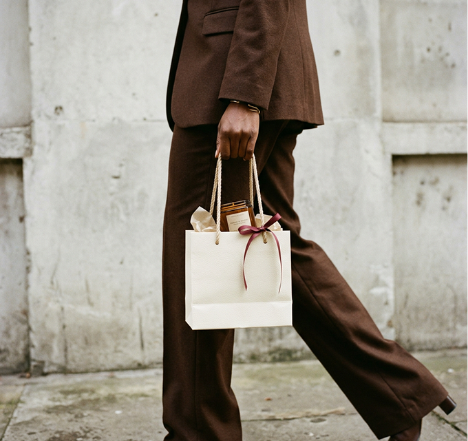 A woman carrying a gift bag tied with a ribbon